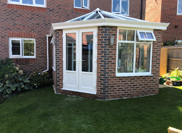 White windows and roof on a modern brick conservatory.